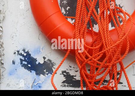 Image rapprochée de la moitié inférieure de la ceinture orange vif avec boucle de cordon orange et fixée à une planche en bois qui a de la peinture blanche écaillée Banque D'Images