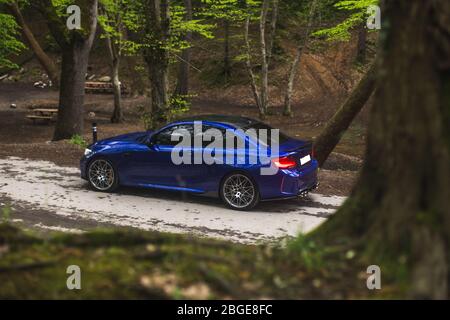 Berline bleue garée dans la forêt profonde Banque D'Images