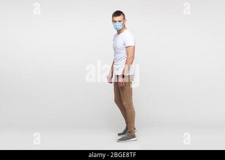 Protection contre les maladies contagieuses, coronavirus. Portrait complet de jeune homme portant un masque hygiénique pour prévenir l'infection, Covid-2019. Intérieur s. Banque D'Images