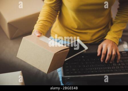 Femme tient une boîte pour préparer à livrer au client selon la commande à la maison.travail à la maison et marketing en ligne ou démarrage petite entreprise c Banque D'Images