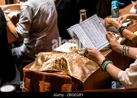 Singapour, octobre 2019. Les gens prient et rendent hommage au Bouddha lors de la cérémonie au Temple Relique de la dent de Bouddha, dans le quartier chinois. Femme tenant livre de prière Banque D'Images