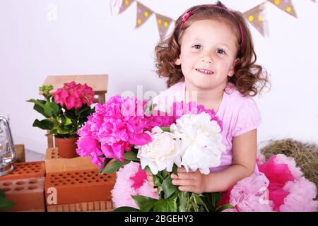 Belle petite fille dans la petite jupe tenant des fleurs sur fond de style champêtre Banque D'Images