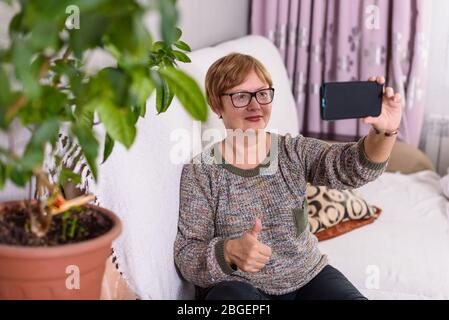 Une femme âgée parle de vidéo de maison et dit que tout va bien. Restez à la maison et soyez sûr à cause du virus corona Banque D'Images
