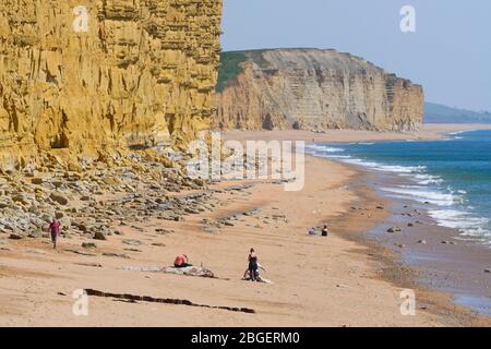 West Bay, Dorset, Royaume-Uni. 21 avril 2020. Météo britannique. Vue sur les falaises de grès emblématiques et la plage presque désertée de West Bay à Dorset dans un après-midi ensoleillé et chaud pendant le verrouillage pandémique du coronavirus. Crédit photo : Graham Hunt/Alay Live News Banque D'Images