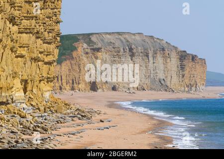 West Bay, Dorset, Royaume-Uni. 21 avril 2020. Météo britannique. Vue sur les falaises de grès emblématiques et la plage presque désertée de West Bay à Dorset dans un après-midi ensoleillé et chaud pendant le verrouillage pandémique du coronavirus. Crédit photo : Graham Hunt/Alay Live News Banque D'Images