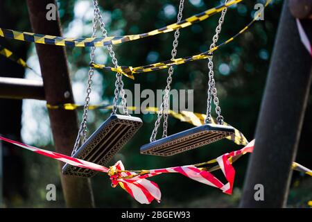 Dortmund, 21.4.2020: Mit Flatterband festgebundene Kinderschukeln auf einem wegen der Coronavirus KRise (Covid-19, SARS-COV-2) und zum Schutz vor Neuinfektionen gesperrten Kinderspielplatz in einer Kleingartenanlage in Dortmund. -- Dortmund, Allemagne, 21 avril 2020: Balançoires pour enfants liées à des rubans dans une aire de jeux pour enfants à Dortmund. Fermé en raison de la crise du coronavirus (Covid-19, SRAS-COV-2) et pour protéger contre les nouvelles infections. Banque D'Images