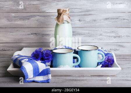 Bouteilles et tasses de lait avec des fleurs de maïs sur plateau en bois Banque D'Images