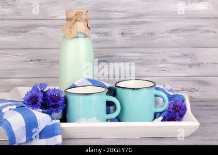 Bouteilles et tasses de lait avec des fleurs de maïs sur plateau en bois Banque D'Images