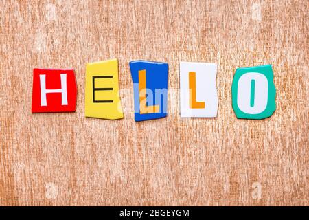 Lettres multicolores dispersées sur fond de bois et mots bonjour. Texture de fond en lettres anglaises. Message BONJOUR sur bois. Salutations, courtoisie Banque D'Images