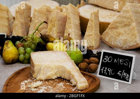 parmigiano reggiano (parmesan), fromage italien typique, 30 mois, sur un marché avec des fruits et planche à découper Banque D'Images