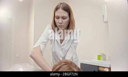 Massage - jeune maître de massage donnant un massage à une jeune femme dans le cabinet - intérieur Banque D'Images