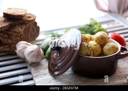 De jeunes pommes de terre bouillies avec des légumes sur table sur fond de fenêtre Banque D'Images