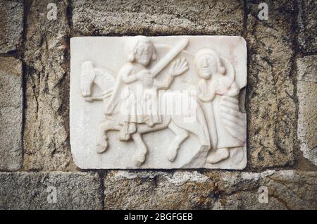 bas relief gothique de Saint Martin de Tours sur le mur extérieur d'une église médiévale. Saint Martin coupe la moitié de son manteau avec l'épée pour se réchauffer Banque D'Images