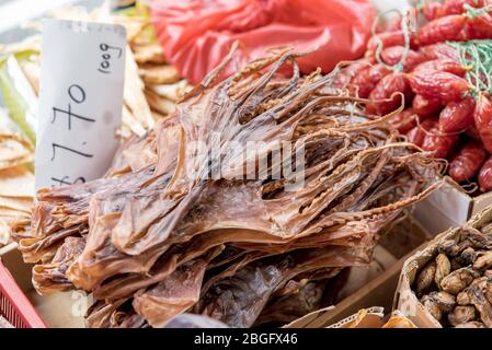 Peau de calmar séchée à vendre dans un panier avec étiquette de prix. En-cas de fruits de mer croustillants orientaux au marché de la rue Banque D'Images