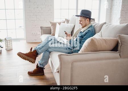 Jeune freelance masculine dans chapeau travaille ordinateur portable dans la salle lumineuse. Concept de voyageur Banque D'Images