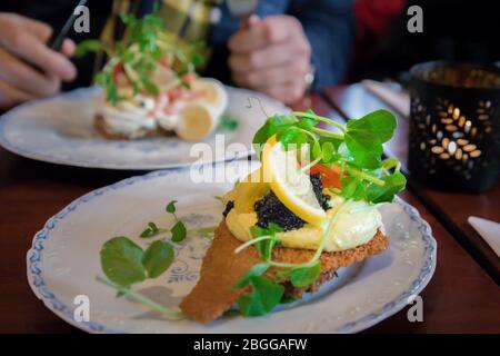 Délicieux smorrebrod danois sanwiches ouvert avec le pain de seigle, du poisson frit, black caviar, citron et pousses vertes Banque D'Images