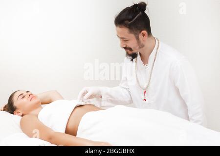 Médecin de médecine orientale faisant des estomacs d'acupuncture pour soulager la douleur d'estomac d'une femme. Médecine alternative Banque D'Images