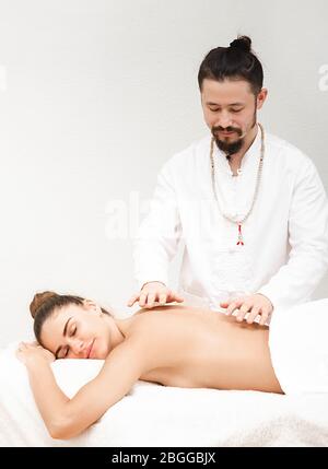 docteur en médecine orientale traditionnelle faisant un massage énergétique sans contact à une belle femme dans un salon de spa. Le corps est nettoyé de l'ener négatif Banque D'Images