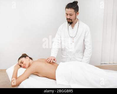 docteur en médecine orientale traditionnelle faisant un massage énergétique sans contact à une belle femme dans un salon de spa. Le corps est nettoyé de l'ener négatif Banque D'Images