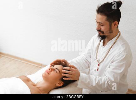 docteur en médecine orientale traditionnelle faisant massage énergétique de la tête. Le massage énergétique reprend la circulation de l'énergie dans le corps Banque D'Images