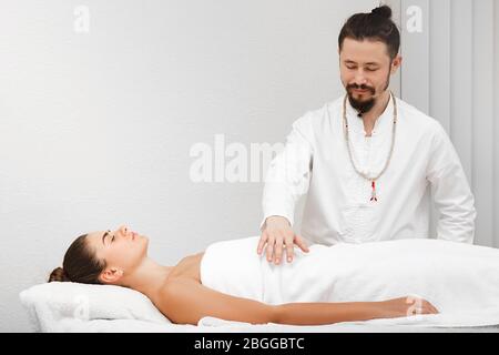 docteur race asiatique faisant massage corporel énergique. Femme recevant une thérapie reiki. Médecine alternative Banque D'Images