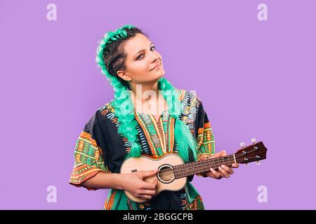 Rastafarian femme avec des deleverrous joue sur l'ukulele. Tresse Kanekalon. Instrument de musique Ukulele Banque D'Images