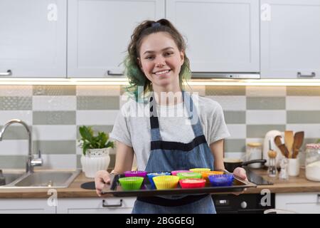 girl dans tablier dans la cuisine avec plateau de préparation de cupcakes en silicone brut. Cuisine maison, cuisine maison Banque D'Images