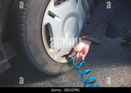 Conducteur d'homme vérifiant la pression d'air et remplir l'air dans les pneus de sa voiture moderne, concept de transport Banque D'Images