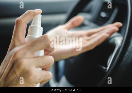 Mains mâles avec un spray désinfectant désinfectez la surface de sa main dans une voiture. Covid-19 pandémie de quarantaine du coronavirus. Protégez-vous et votre aimé Banque D'Images