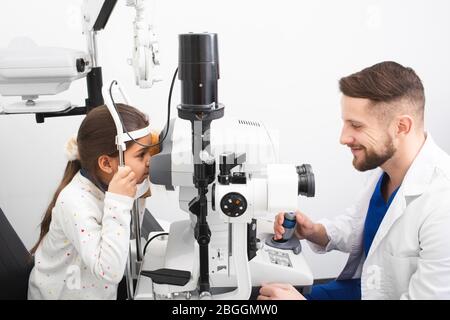 Le médecin mâle vérifie la vue d'une fille sur l'équipement moderne dans la clinique. Le sonomètre mesure la pression oculaire du patient. Correction de la vision Banque D'Images