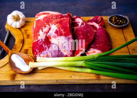 Faire cuire de la viande sur planche en bois avec de l'oignon et de l'ail Banque D'Images