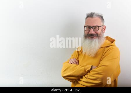 Portrait d'homme barbu mûr à poil gris dans un sweat à capuche jaune sur fond blanc, foyer sélectif Banque D'Images