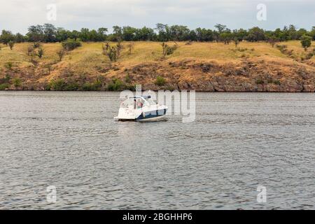 KHORTYTSIA, UKRAINE - 28 JUIN 2019: Le bateau de plaisance navigue près de l'île de Khortytsia au coucher du soleil. Khortytsia est la plus grande île de la rivière DNI Banque D'Images