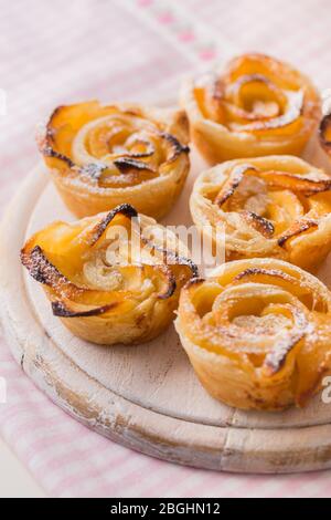 Délicieuse pâte feuilletée aux pommes en forme de rose sur planche en bois Banque D'Images