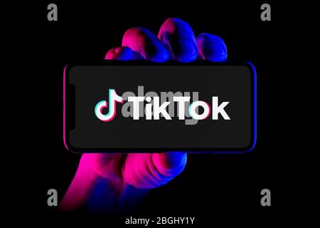 Un smartphone affichant le logo Tik Tok est placé sur un fond noir (usage éditorial uniquement). Banque D'Images
