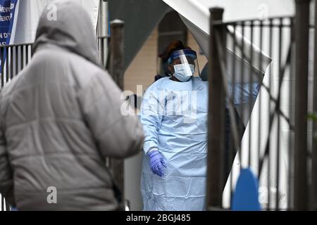 New York City, États-Unis. 21 avril 2020. Un professionnel de la santé portant un équipement de protection personnelle tire un rabat de tente lorsqu'il appelle à renvoyer une personne attendant d'être testée pour COVID-19 dans les hôpitaux sanitaires/Gotham Health de Harlem, Sydenham, à New York, NY, le 21 avril 2020. Le Coronavirus a eu un impact disproportionné sur les communautés africaines américaines. (Anthony Behar/Sipa USA) crédit: SIPA USA/Alay Live News Banque D'Images