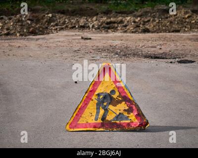 Panneau d'avertissement de l'avance sur route. La route est vieille et endommagée Banque D'Images