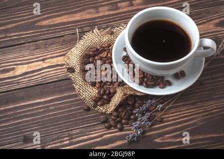 Tasse avec café noir, grains de café et branches de lavande sur un plan d'examen en bois. Vue de dessus Banque D'Images