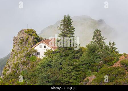 Une maison blanche avec un toit carrelé dans les montagnes parmi les nuages. Banque D'Images