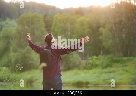 L'homme barbu a levé les mains jusqu'au soleil couchant. Vue magnifique sur la vallée Banque D'Images