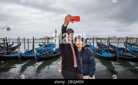 Couple thaïlandais prenant le selfie devant les gondoles garées à Venise Banque D'Images