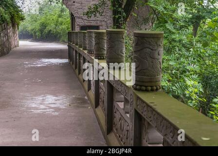 Fengdu, Chine - 8 mai 2010 : Ville fantôme, sanctuaire historique. Pierre brune avec pont vert de moisissure de l'impuissance dans la pluie et avec le feuillage vert autour. Banque D'Images