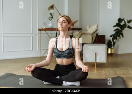 Jolie femme pratique le yoga sur un fond intérieur. Relaxation et méditation en position lotus. Banque D'Images