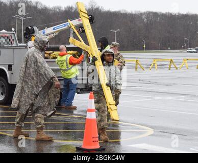 Les membres de la Garde nationale de l'Armée de New York, avec les travailleurs du département de la route Brookhaven, assemblent des barricades dans un parc de stationnement SUNY Stony Brook, dans le ruisseau Stony, dans l'État de New York, le 17 mars 2020. Les barricades sont créées pour créer des voies pour les voitures dans un emplacement de collecte de l'écouvillon du drive dans le cadre de la réponse multi-agence à COVID-19. (ÉTATS-UNIS Photo de la Garde nationale aérienne par Sean Madden, agent principal de l'aviation) Banque D'Images