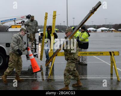 Les membres de la Garde nationale de l'Armée de New York, avec les travailleurs du département de la route Brookhaven, assemblent des barricades dans un parc de stationnement SUNY Stony Brook, dans le ruisseau Stony, dans l'État de New York, le 17 mars 2020. Les barricades sont créées pour créer des voies pour les voitures dans un emplacement de collecte de l'écouvillon du drive dans le cadre de la réponse multi-agence à COVID-19. (ÉTATS-UNIS Photo de la Garde nationale aérienne par Sean Madden, agent principal de l'aviation) Banque D'Images