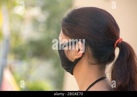 Femme indienne commune en mât noir pour protéger contre le covid-19. Virosée de l'arrière, bg flou pendant la pandémie de Covid-19 de Coronavirus Banque D'Images