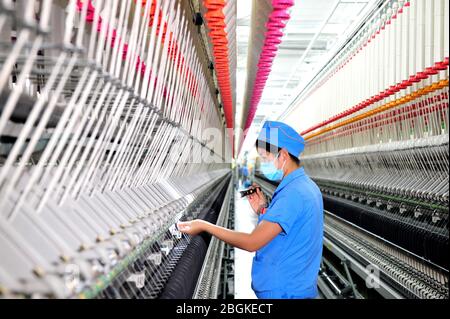 Le personnel de l'usine de filature Tianhong, une usine locale qui permet une reprise complète de la production, travaille sur une chaîne de production automatisée, comté de Suining, Xuzhh Banque D'Images