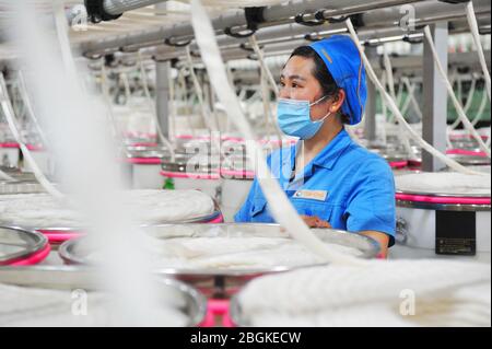 Le personnel de l'usine de filature Tianhong, une usine locale qui permet une reprise complète de la production, travaille sur une chaîne de production automatisée, comté de Suining, Xuzhh Banque D'Images