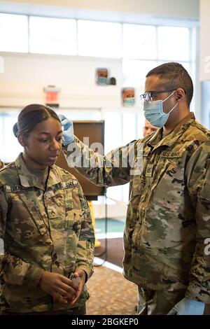 PFC. Nicholas Leemoon, 1171ème soutien de la région de la société médicale, effectue un dépistage médical sur le Cpl. Catherine Brooks, 156ème Bataillon de signaux expéditionnaires, afin d'aider à atténuer le risque de COVID-19 à Romulus, au Michigan, le 6 avril 2020. La Garde nationale du Michigan est ici pour servir les communautés; ce sont des voisins et des partenaires durant ces périodes difficiles. ( photo de la Garde nationale de l'Armée de terre par le 2ème lieutenant Ashley Goodwin) Banque D'Images