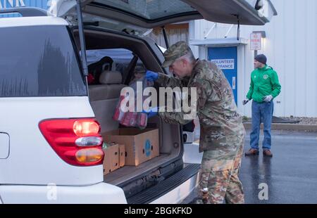 CPT. Eric Bolin, officier d'entraînement du 1 Bataillon 293 Infantry Regiment, charge les provisions à l'arrière d'un véhicule à la Community Harvest Food Bank à fort Wayne, Ind. Le 28 mars 2020. La Community Harvest Food Bank et la Garde nationale de l'Indiana ont travaillé ensemble pour aider à répondre aux besoins de Hoosiers qui luttent pour nourrir leurs familles pendant la crise de la COVID-19. Banque D'Images